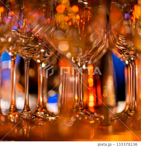 Elegant scene of wine being poured into glasses aligned in a row, showcasing the rich colors and graceful flow of the liquid, set against a dark, warm background, ideal sophisticated dining settings 133378136