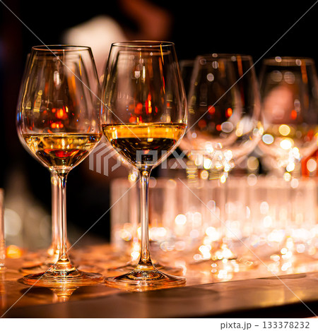 Elegant scene of wine being poured into glasses aligned in a row, showcasing the rich colors and graceful flow of the liquid, set against a dark, warm background, ideal sophisticated dining settings Elegant scene of wine being poured into glasses aligned in a row, showcasing the rich colors and graceful flow of the liquid, set against a dark, warm background, ideal sophisticated dining settings 133378232