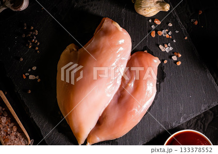 Raw meat chicken breast with thyme herbs and whole pepper on black backdrop 133378552