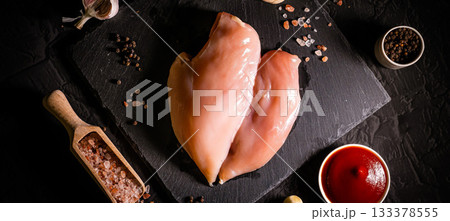Raw meat chicken breast with thyme herbs and whole pepper on black backdrop Raw meat chicken breast with thyme herbs and whole pepper on black backdrop 133378555
