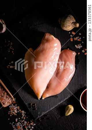 Raw meat chicken breast with thyme herbs and whole pepper on black backdrop 133378561