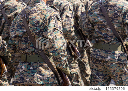 Multiple men in camouflage uniforms carrying rifles outdoors at sunny day Multiple men in camouflage uniforms carrying rifles outdoors at sunny day 133379296