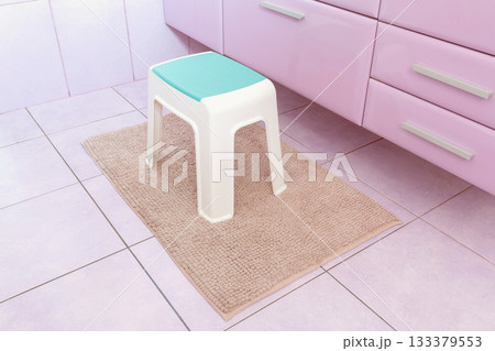 Plastic chair on rectangle beige carpet in bathroom 133379553