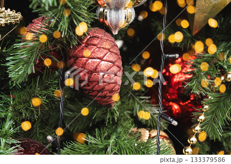 Christmas tree with red ball as pine cone and lights garland. Xmas card. Close up. Winter. Outdoors. 133379586