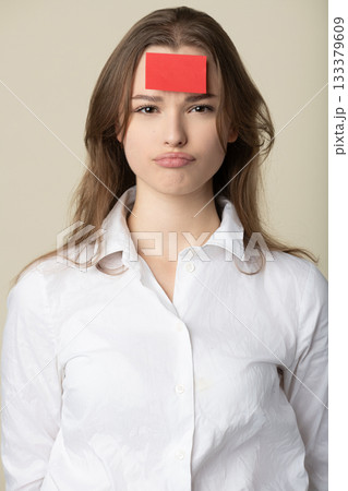 Woman with red sticker note on her forehead 133379609