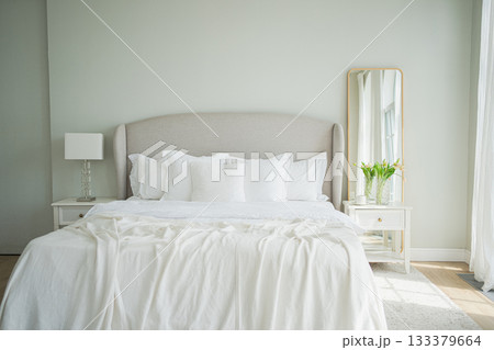 Stylish loft bedroom interior. Spacious design apartment with light walls large windows big bed. Clean modern decoration with elegant furniture in minimalist Scandinavian style Stylish loft bedroom interior. Spacious design apartment with light walls large windows big bed. Clean modern decoration with elegant furniture in minimalist Scandinavian style 133379664