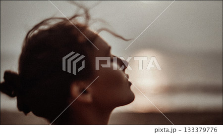Young woman enjoying the sunset. A woman's profile is silhouetted against a soft, muted sunset, her hair gently blowing in the wind, evoking a sense of peace and tranquility. This is AI-generated item Young woman enjoying the sunset. A woman's profile is silhouetted against a soft, muted sunset, her hair gently blowing in the wind, evoking a sense of peace and tranquility. This is AI-generated item 133379776