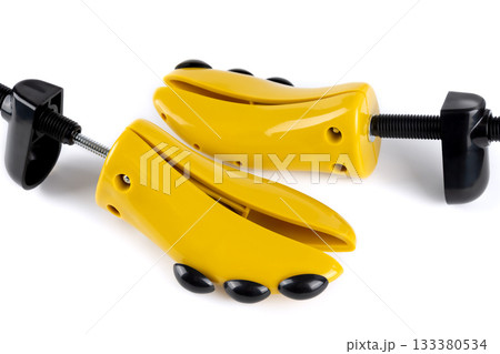 Pair plastic shoe stretchers with adjustment knobs, screws for reshaping shoes on white background. 133380534