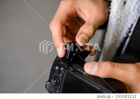 Photographer inserts battery into professional camera outdoor while having a photoshoot. Professional artist has run out of battery life in camera while shooting pictures 133381212