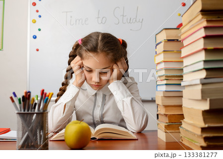 Bored elementary learner reading a book. Concept of studying, reading 133381277