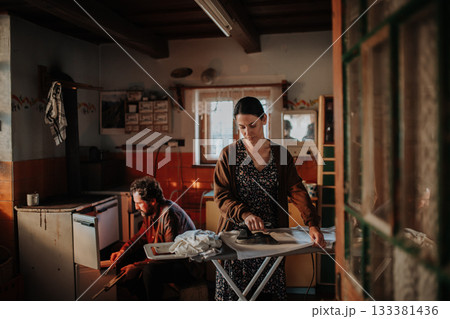 Couple doing household chores in an old rural home. 133381436