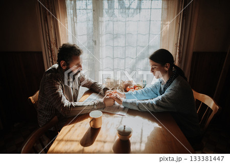 Portrait of poor mature couple sitting at table, fearing the future. Portrait of poor mature couple sitting at table, fearing the future. 133381447