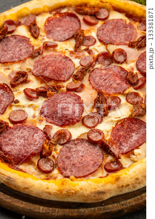 Close up pepperoni pizza with salami slices and melted cheese on wooden board 133381871