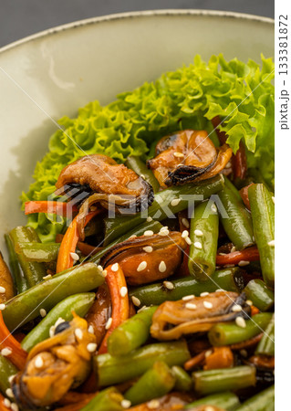 Mussel and green bean salad with sesame in a ceramic bowl on dark stone Mussel and green bean salad with sesame in a ceramic bowl on dark stone 133381872