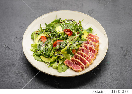 Seared tuna salad with avocado, arugula and sesame on plate, healthy gourmet lunch 133381878