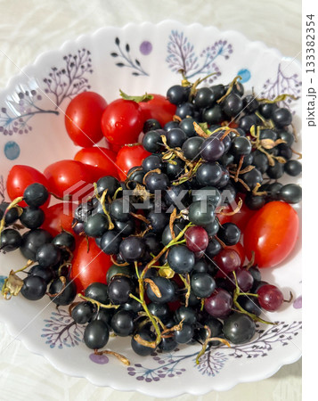 Fresh Cherry Tomatoes and Black Currants in Decorative Bowl Fresh Cherry Tomatoes and Black Currants in Decorative Bowl 133382354