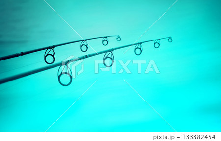 Two fishing rods over blue lake water 133382454