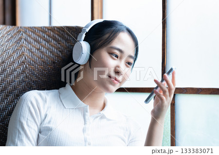 ヘッドホンでスマホ音楽を聴く若い女性 133383071