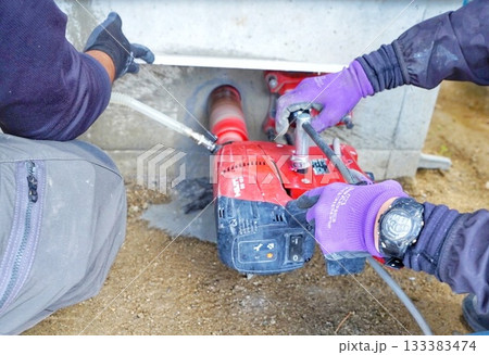 電動穴あけ工具を使ってコンクリート基礎の穴あけ工事している様子 133383474