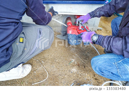 電動穴あけ工具を使ってコンクリート基礎の穴あけ工事している様子 133383480