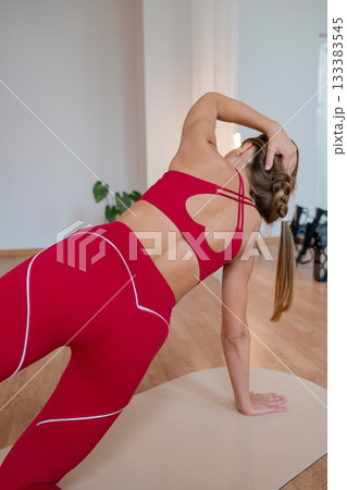 Active women execute coordinated side planks with trainer guidance in welllit studio setting 133383545