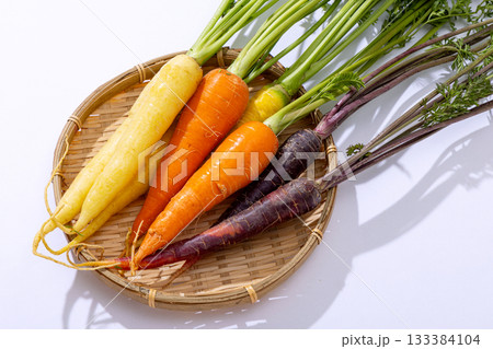カラフルな葉つきニンジンのざるもり 133384104