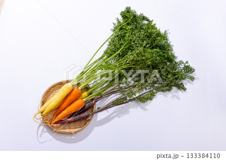 カラフルな葉つきニンジンのざるもり 133384110