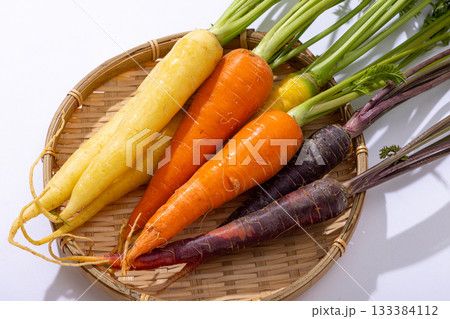 カラフルな葉つきニンジンのざるもり 133384112