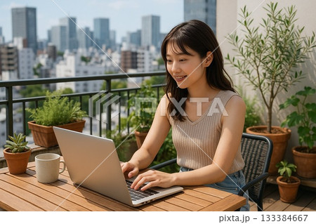 都会のマンションのベランダでPC作業をする笑顔の女性 133384667
