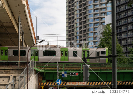 Train passing over a bridge in a modern Japanese city 133384772