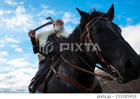 A fierce Viking warrior on horseback, wielding an axe, stands against a dramatic sunset sky with clouds and mountains, embodying strength, exploration, and ancient legend. A fierce Viking warrior on horseback, wielding an axe, stands against a dramatic sunset sky with clouds and mountains, embodying strength, exploration, and ancient legend. 133385458