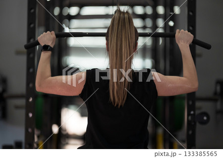 Weightlifting woman training indoors in a gym, focused on strength during an upper body workout session 133385565