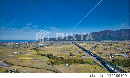 北アルプスを背景にした富山県入善町を走る北陸新幹線の高架橋付近の様子 133386169