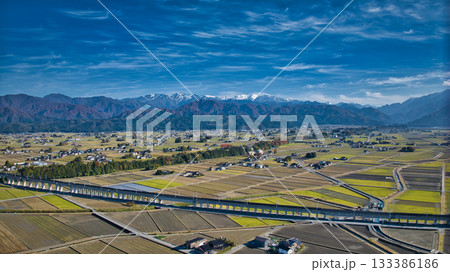 北アルプスを背景にした富山県入善町を走る北陸新幹線の高架橋付近の様子 133386186