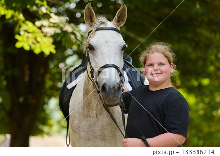 Girl with her horse in nature, a young rider and her equine friend, enjoying the outdoors, equestrian lifestyle, friendship and bonding, summer day, happy child. Girl with her horse in nature, a young rider and her equine friend, enjoying the outdoors, equestrian lifestyle, friendship and bonding, summer day, happy child. 133386214