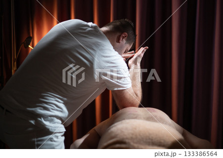 Professional therapist applying deep tissue massage techniques on a male client lying on massage table with towel, therapeutic bodywork for muscle pain relief and relaxation. Professional therapist applying deep tissue massage techniques on a male client lying on massage table with towel, therapeutic bodywork for muscle pain relief and relaxation. 133386564