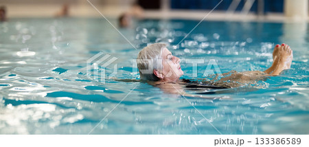 Senior Woman Swimming and Relaxing in Indoor Pool Senior Woman Swimming and Relaxing in Indoor Pool 133386589