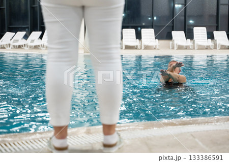 Instructor leading aquatic fitness training for group senior women in a swimming pool. Concept of health, exercise, wellness, water therapy, and active aging lifestyle 133386591