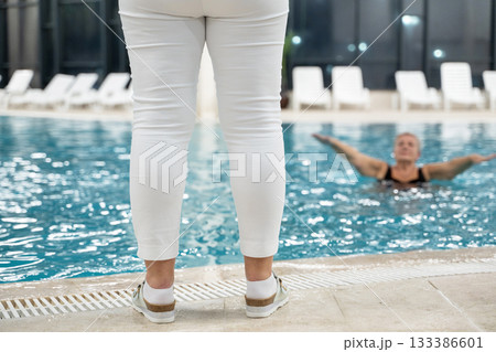 Instructor leading aquatic fitness training for group senior women in a swimming pool. Concept of health, exercise, wellness, water therapy, and active aging lifestyle 133386601