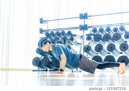 トレーニングジムで腕立てをする若い男性 トレーニングジムで腕立てをする若い男性 133387228