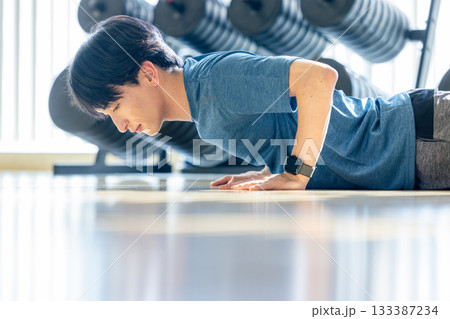 トレーニングジムで腕立てをする若い男性 133387234