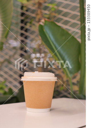 Warm coffee cup on a table near tropical plants 133389450