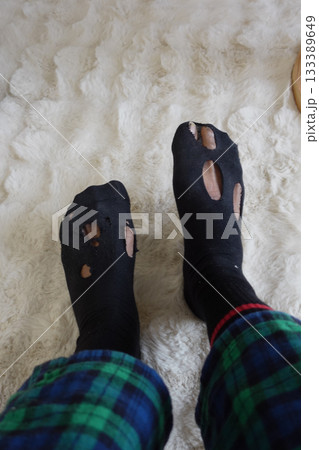 Worn socks with holes on a cozy carpeted floor Worn socks with holes on a cozy carpeted floor 133389649