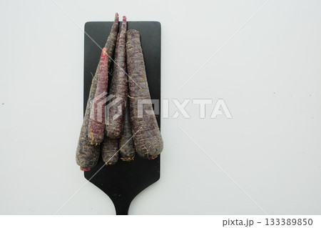 Fresh purple carrots arranged on a wooden board 133389850