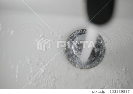 Flowing water from faucet into a white sink 133389857