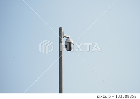 Surveillance camera mounted on a pole in clear sky 133389858
