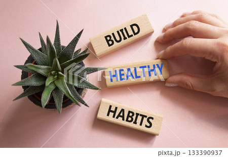 Healthy habits symbol. Concept word Build Healthy habits on wooden blocks. Doctor hand. Beautiful pink background with succulent plant. Healthy lifestyle and Healthy habits concept. Copy space Healthy habits symbol. Concept word Build Healthy habits on wooden blocks. Doctor hand. Beautiful pink background with succulent plant. Healthy lifestyle and Healthy habits concept. Copy space 133390937