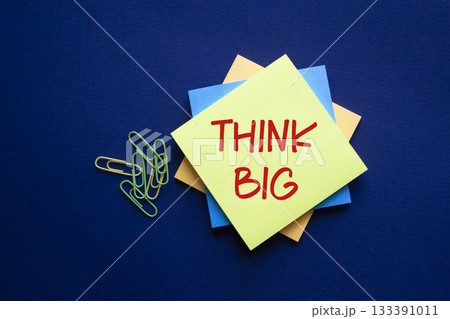 Think big symbol. Yellow sticky note with words Think Big. Beautiful deep blue background. Business and Think big concept. Copy space. Think big symbol. Yellow sticky note with words Think Big. Beautiful deep blue background. Business and Think big concept. Copy space. 133391011