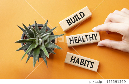 Healthy habits symbol. Concept word Build Healthy habits on wooden blocks. Doctor hand. Beautiful orange background with succulent plant. Healthy lifestyle and Healthy habits concept. Copy space 133391369