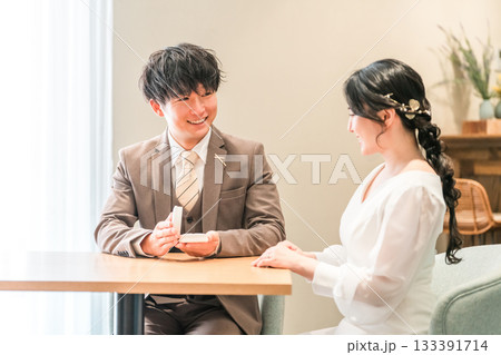 レストランでプロポーズをする男性と指輪を受け取る女性 133391714
